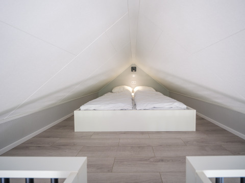 Dormitorio abuhardillado con techo bajo y cama doble en Summer Lodge, Parque y Marina Rhederlaagse Meren, Países Bajos.