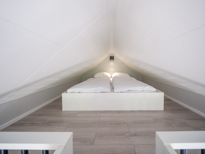 Attic bedroom with low ceiling and double bed at Summer Lodge, Recreation park and Marina Rhederlaagse Meren, Netherlands.