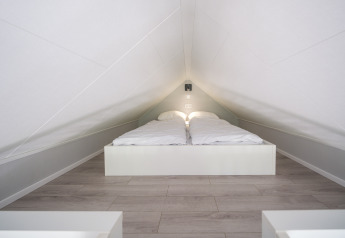 Dormitorio abuhardillado con techo bajo y cama doble en Summer Lodge, Parque y Marina Rhederlaagse Meren, Países Bajos.