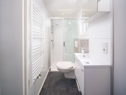 Moderne og lys badeværelse i Summer Lodge ved Rhederlaagse Meren, med bruser, håndvask og toilet.