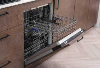 Open dishwasher with pulled-out rack in the kitchen at Summer Lodge, Rhederlaagse Meren, Netherlands.