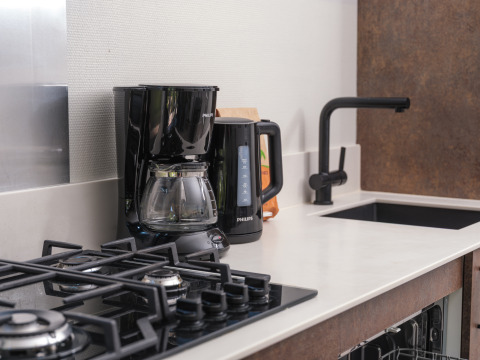 Kitchenette moderne avec cafetière, bouilloire électrique, gazinière et évier au Summer Lodge aux Pays-Bas.