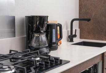 Cocina compacta con cafetera, hervidor, estufa de gas y fregadero en Summer Lodge, Países Bajos.