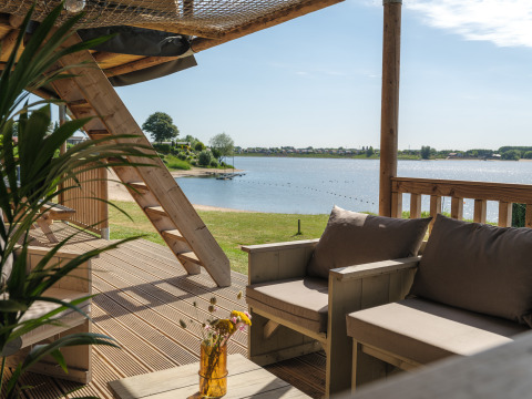 Vista desde la terraza de la tienda safari en Rhederlaagse Meren con sofá y lago al fondo.