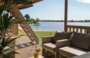 Vista desde la terraza de la tienda safari en Rhederlaagse Meren con sofá y lago al fondo.