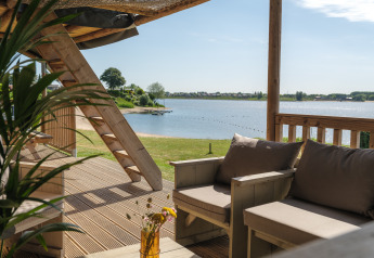 Vue depuis la terrasse d’une tente safari au Rhederlaagse Meren avec canapé et lac en arrière-plan.