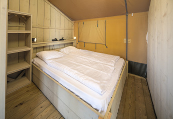 Binnenaanzicht van de Safari tent Ranger met tweepersoonsbed en planken in recreatiepark Rhederlaagse Meren.
