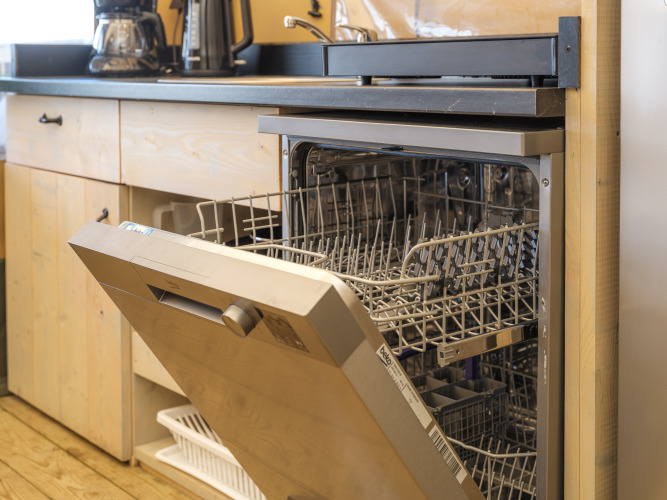 Open dishwasher in the kitchen of a safari tent at Rhederlaagse Meren recreation park in the Netherlands.