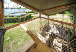 Vue d’une terrasse de tente safari avec filets et sièges, donnant sur la marina de Rhederlaagse Meren, Pays-Bas.
