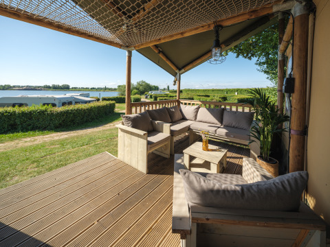 Zona de estar exterior de la Safari tent Ranger con sofás y vistas a la marina en Rhederlaagse Meren, Países Bajos.
