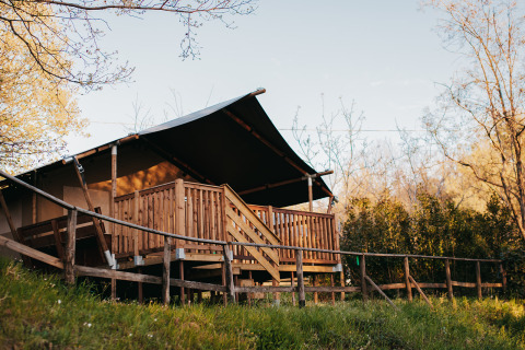 Safari-Zelt mit sanitären Einrichtungen auf Camping Lucherino in Italien, umgeben von Natur und Bäumen.