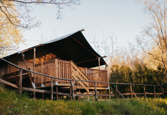 Safari-Zelt mit sanitären Einrichtungen auf Camping Lucherino in Italien, umgeben von Natur und Bäumen.