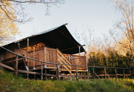 Safaritent met sanitaire voorzieningen op Camping Lucherino in Italië, omgeven door natuur en bomen.