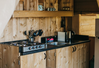 Trætekøkken i en safaritelt på Camping Lucherino, Italien, med gaskomfur og åbne hylder.