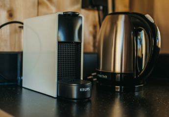Een foto van een koffiemachine en waterkoker op een aanrecht in een safaritent op Camping Lucherino, Italië.