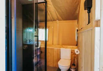 Badkamer in safaritent met douche en toilet bij Camping Lucherino in Italië, warm interieur.