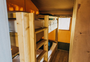 Indvendigt billede af Safari-telt med køjesenge og trægulv på Camping Lucherino i Italien.