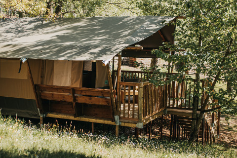 Safari tent met eigen sanitair en houten terras bij Camping Lucherino in Italië, omgeven door natuur.