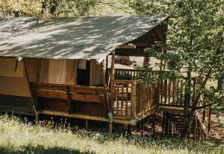 Safari tent with private sanitary facilities and wooden terrace at Camping Lucherino, Italy, in nature.