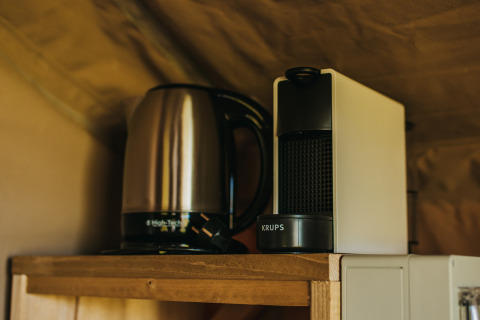 Waterkoker en koffiezetapparaat op een houten plank in Safari Tent Garden bij Camping Lucherino, Italië.