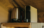 Waterkoker en koffiezetapparaat op een houten plank in Safari Tent Garden bij Camping Lucherino, Italië.
