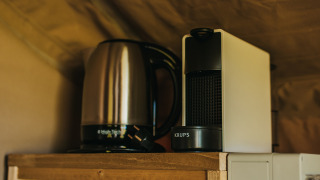 Bollitore elettrico e macchina da caffè su mensola in legno nella Safari Tent Garden al Camping Lucherino, Italia.