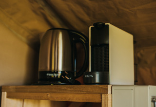 Elkedel og kaffemaskine på en træhylde inde i Safari Tent Garden på Camping Lucherino i Italien.