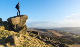 Een wandelaar staat op een grote rots en kijkt uit over het landschap nabij Inkpen in Zuidoost-Engeland.