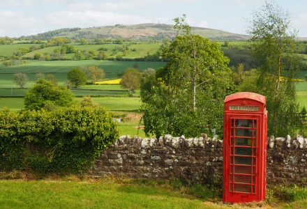 Rode telefooncel aan een stenen muur met groene velden bij Inkpen, Zuidoost-Engeland, Verenigd Koninkrijk.