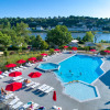 Outdoor pool with red umbrellas and loungers at Flower Camping L'Ile d'Offard, Pays de la Loire, France.
