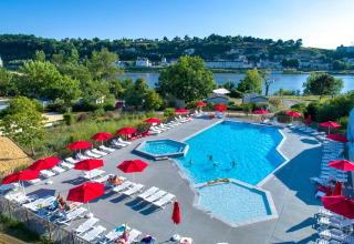 Outdoor pool with red umbrellas and loungers at Flower Camping L'Ile d'Offard, Pays de la Loire, France.