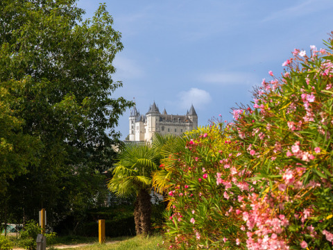 Vista de un castillo a lo lejos entre arbustos y flores en Flower Camping L'Ile d'Offard, Pays de la Loire.