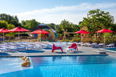 Piscina al aire libre en Flower Camping L'Ile d'Offard con tumbonas y sombrillas rojas en Pays de la Loire, Francia.