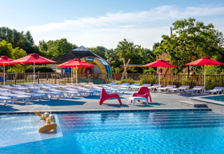 Piscina all'aperto a Flower Camping L'Ile d'Offard con lettini, ombrelloni rossi in Pays de la Loire, Francia.
