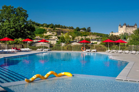 Piscine extérieure avec parasols rouges et vue sur château au Flower Camping L'Ile d'Offard, en France.
