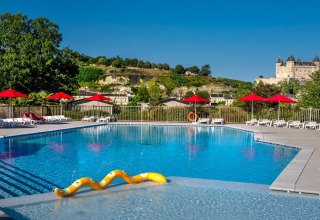 Piscine extérieure avec parasols rouges et vue sur château au Flower Camping L'Ile d'Offard, en France.