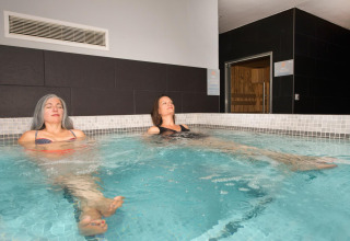 Zwei Frauen entspannen sich im Innenpool bei Flower Camping L'Ile d'Offard im Pays de la Loire, Frankreich.