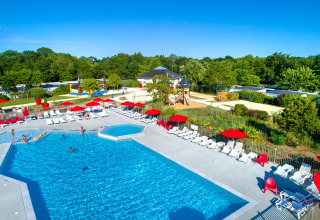 Piscina al aire libre con tumbonas y sombrillas rojas en Flower Camping L'Ile d'Offard, Pays de la Loire, Francia.