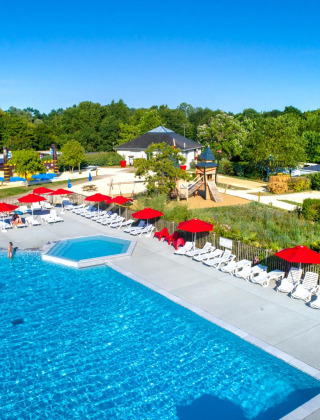 Buitenzwembad met ligbedden en rode parasols bij Flower Camping L'Ile d'Offard in Pays de la Loire, Frankrijk.