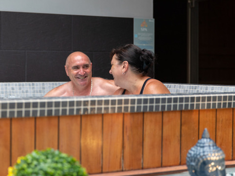 Pareja relajándose y sonriendo en un jacuzzi en Flower Camping L'Ile d'Offard, Pays de la Loire, Francia.