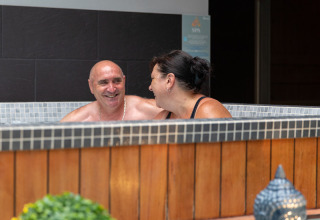 Couple relaxing and smiling in a hot tub at Flower Camping L'Ile d'Offard, Pays de la Loire, France.