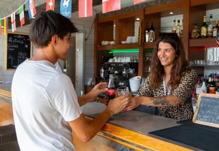 Una camarera sonriente atiende a un cliente en la barra de Flower Camping L'Ile d'Offard, Pays de la Loire.