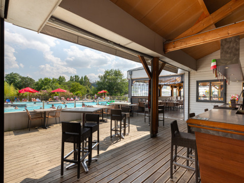 Udendørs bar og siddeområde med udsigt til swimmingpool og gæster på Flower Camping L'Ile d'Offard.
