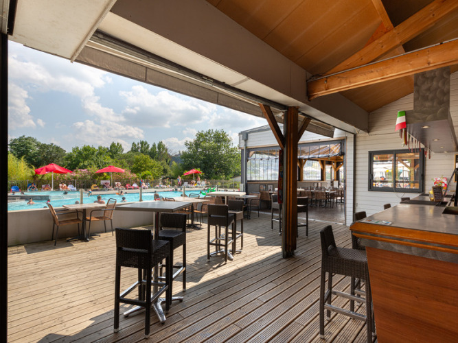 Overdekt terras met bar en uitzicht op het zwembad bij Flower Camping L'Ile d'Offard in Frankrijk.