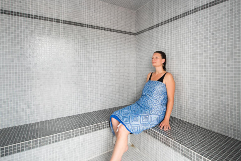 Woman relaxing in a steam room at Flower Camping L'Ile d'Offard, a holiday park in Pays de la Loire, France.