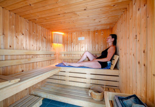 Vrouw ontspant in een houten sauna bij Flower Camping L'Ile d'Offard in Pays de la Loire, Frankrijk.