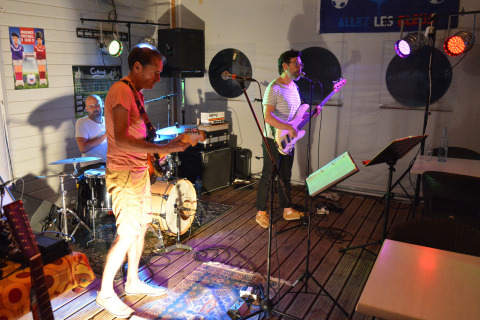 Una band si esibisce dal vivo su un piccolo palco con luci colorate al Flower Camping L'Ile d'Offard, Francia.