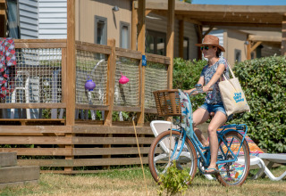 Kvinde cykler ved siden af en terrasse i sommerhus ved Flower Camping L'Ile d'Offard, Pays de la Loire, Frankrig.