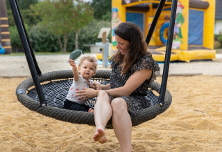 Mamma e bambino si divertono sull'altalena al parco giochi di Flower Camping L'Ile d'Offard, Pays de la Loire, Francia.