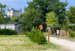 Ferienpark Flower Camping L'Ile d'Offard in Pays de la Loire, Frankreich, mit Schloss im Hintergrund und Gästen.